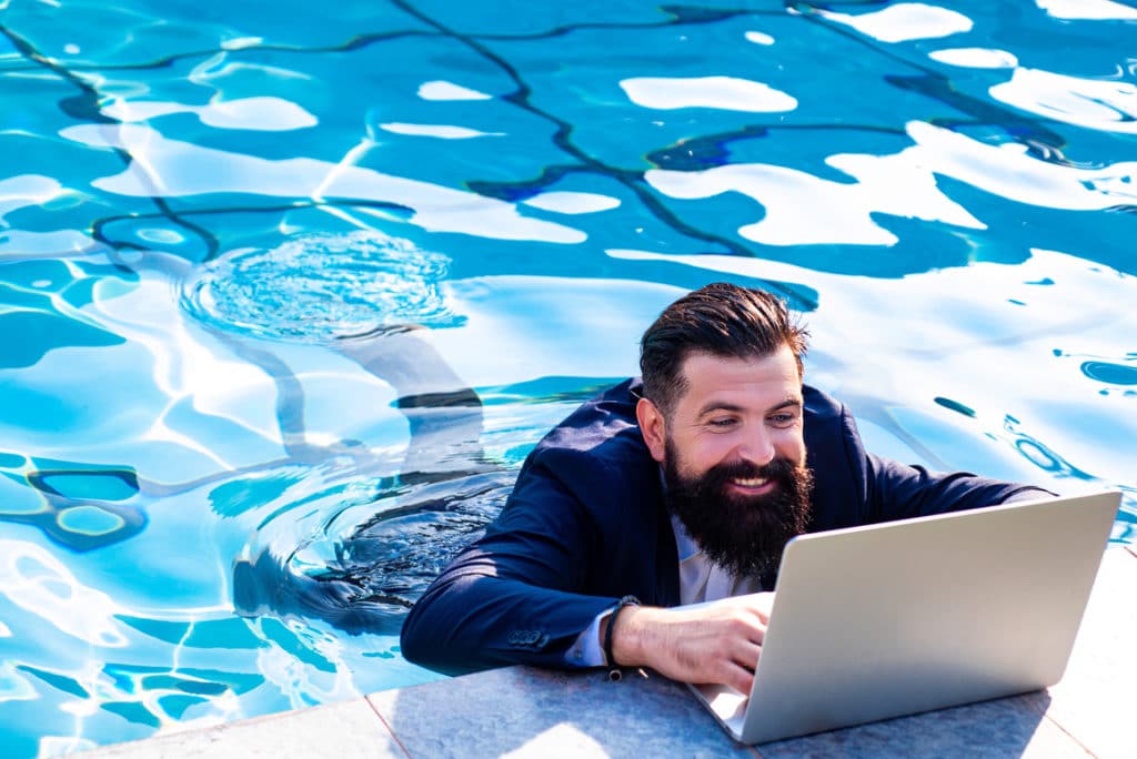 man on laptop in swimming pool working on his business online presence