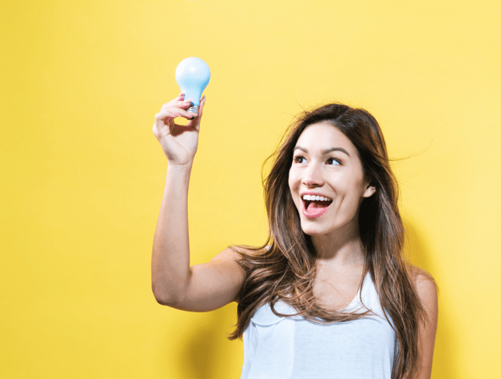 woman holding a lightbulb up and smiling after coming up with a brand name